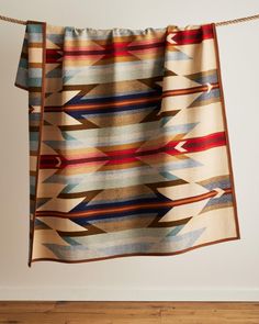 a multicolored blanket hanging from a rope on a wooden floor next to a wall