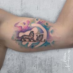 a woman's arm with a tattoo of two cats sitting on top of the moon