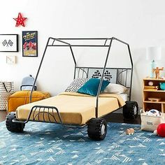 a child's bedroom with a metal bed frame and toy cars on the floor