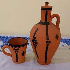 two orange vases sitting next to each other on a white tablecloth covered table