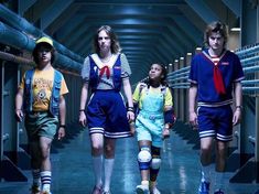 four young people walking down a hallway in shorts and shirts with knee pads on their feet