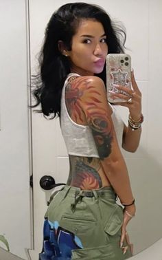 a woman taking a selfie in front of a mirror with tattoos on her body