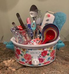 a flowered pot filled with kitchen utensils