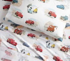 two sheets with cars printed on them are laying next to each other in the bed