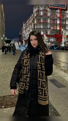 a woman is standing on the sidewalk in front of a building at night with her hands behind her back