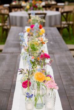 a long table with vases filled with flowers on it