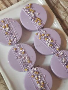 some purple and gold decorated cookies on a white plate with beaded trimmings