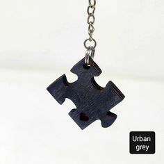 a wooden puzzle piece is attached to a metal chain with a red heart on it