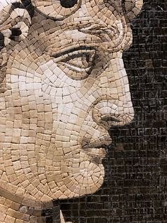 a close up of a face made out of small tiles on a brick wall in the shape of a man's head