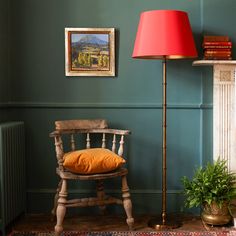 a chair with a red lamp next to it and a painting on the wall behind it