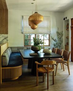 a dining room table with chairs and a bench in front of a window that looks out onto the outdoors