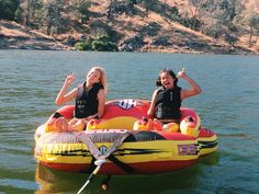 two girls in life vests on an inflatable raft