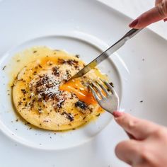 someone is eating an omelet on a white plate with a knife and fork