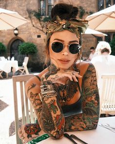 a woman with tattoos sitting at a table