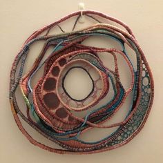 a circular piece of art made out of different colored beads on a white wall with one circle in the middle