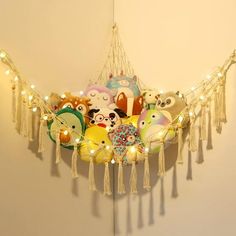 a bunch of stuffed animals are hanging from the ceiling with string lights on it's sides