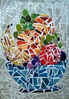 a mosaic glass bowl filled with fruit on top of a white table covered in paper