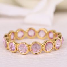 a close up of a ring with pink stones on the side and gold rings around it