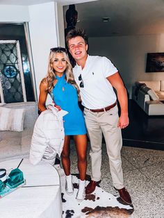 a man and woman standing next to each other in a living room with cow hide rugs on the floor