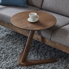 a wooden table sitting on top of a carpeted floor next to a gray couch