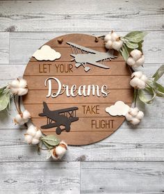 a wooden sign with the words let your dreams take flight and an airplane on it