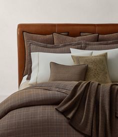 a bed with brown and white comforters, pillows and blankets on top of it