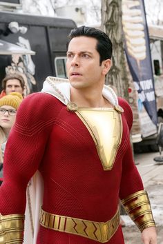 the man is dressed in a red and gold costume with his hands on his hips