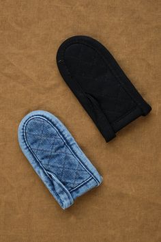 a pair of oven mitts sitting on top of a brown cloth covered table next to an oven mitt