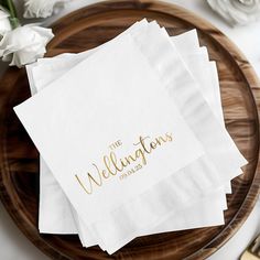 three white napkins with gold foil lettering on them sitting on a wooden platter