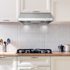 a stove top oven sitting inside of a kitchen next to white cupboards and drawers