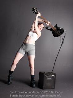 a woman in short shorts holding an electric guitar over her head and standing next to a amp