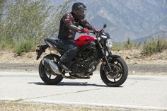 a man riding on the back of a red motorcycle