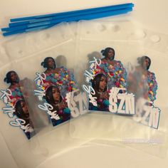 three plastic bags with stickers on them and some blue straws in the background