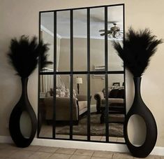 a mirror that has some black feathers on it in the middle of a living room