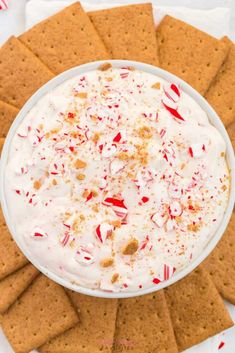 a white bowl filled with whipped cream surrounded by crackers and candy canes on top