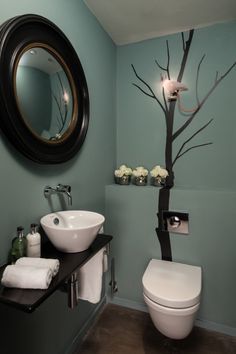 a bathroom with a tree painted on the wall next to a white toilet and sink