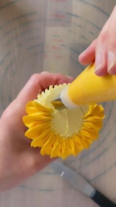 someone is using a yellow toothbrush to clean the bottom of a plastic cup that has a flower on it