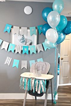 a baby's room decorated with blue and white balloons, streamers and decorations