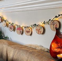 a string of wooden slices hanging from a wall next to a vase filled with candles