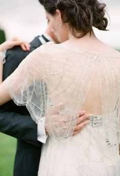 the back of a bride's dress as she stands next to her groom