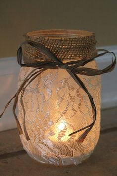 a mason jar filled with lace and a lit candle