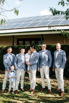 a group of men standing next to each other in front of a solar panel roof