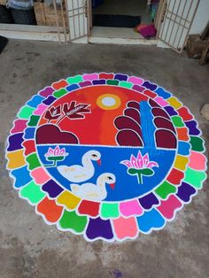 a colorful circular design on the ground in front of a caged area with other items