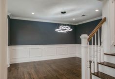 an empty living room with wood floors and white railings, painted in dark blue