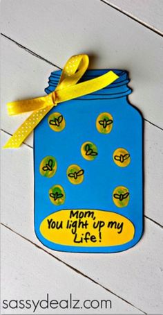 a blue mason jar with yellow ribbon hanging from it's side and the words mom, you light up my life