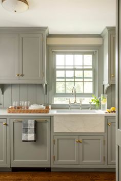 a kitchen with gray cabinets and white counter tops