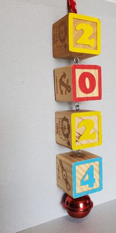 three wooden blocks with numbers on them are hanging from a hook in the wall next to a red ball