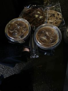 three plastic containers filled with food sitting on top of a black table next to other items