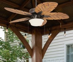 a ceiling fan mounted to the side of a wooden structure in front of a house