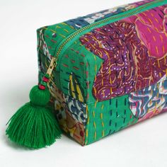 a multicolored cosmetic bag with tassels on the front and side, sitting on a white surface